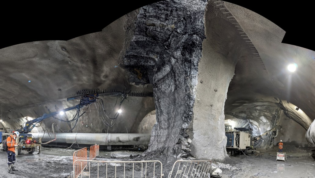 Underground excavation around a central rock pillar, with shotcrete and construction equipment.